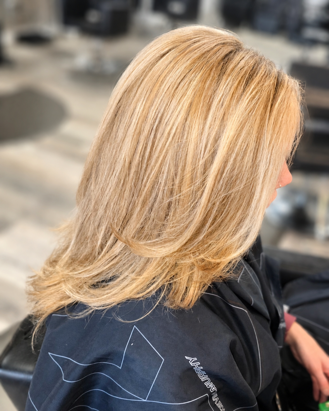 Medium length blonde hair with warm dimensional highlights, layered cut